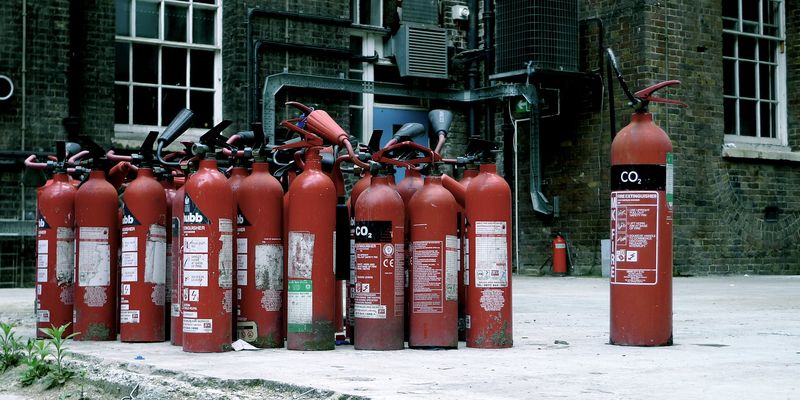 A photo of a collection of fire hydrants behind a London building. It looks like the big one is giving the other ones a lecture