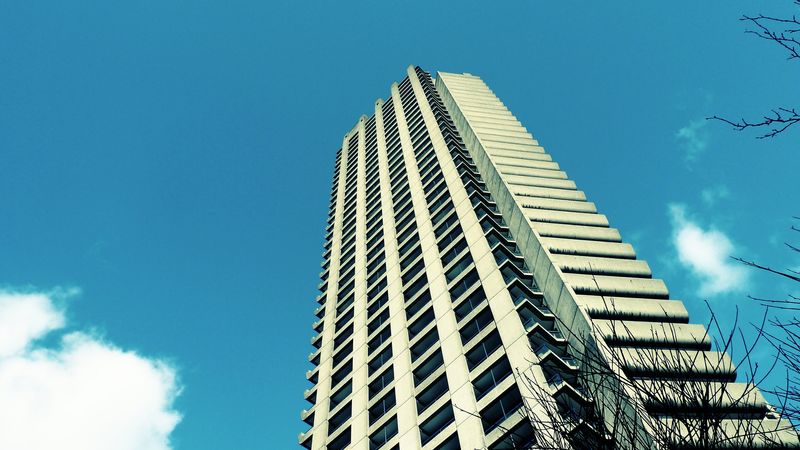 A photo of one of the Barbican towers, set  against a blue, cloudless sky