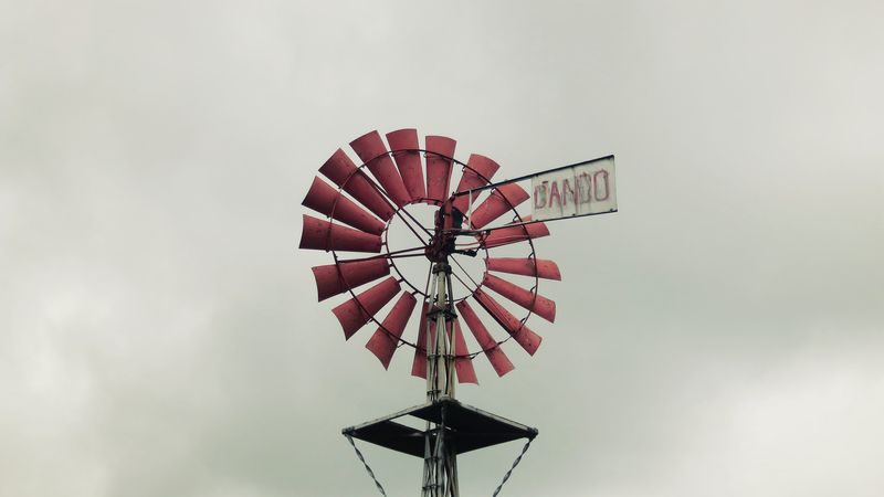 A photo of a red windmill on a tower, set against a gloomy sky, in the Amberley Museum