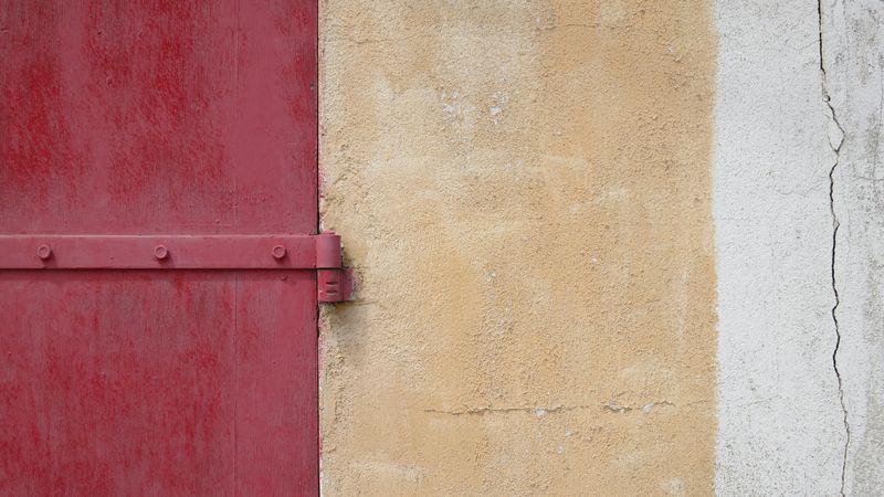 A photo of a red, beige and white painted farm wall in northern France