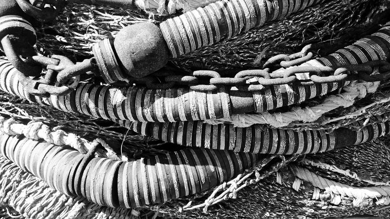 A black and white photo of a load of nautical chains, striped cables and ropes