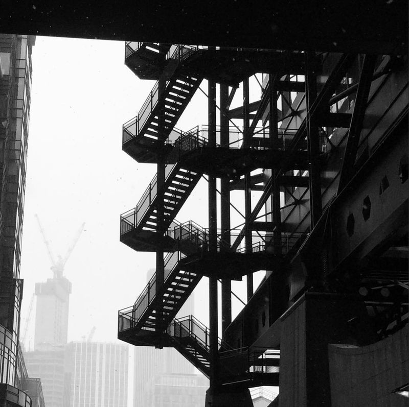 A black and white photo of a fire escape silhouetted against the sky in London